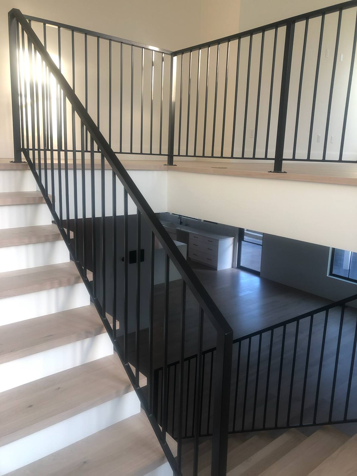 Black vertical-picket metal stair railing by Cascade Mobile Welding