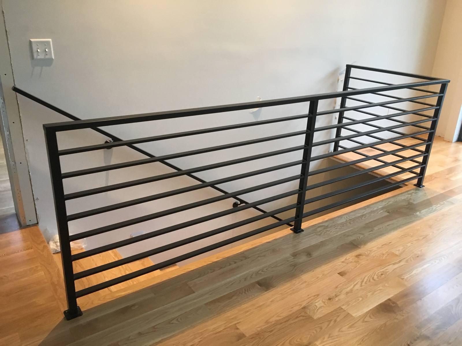 Modern horizontal-bar metal guardrail at an upstairs landing — custom built and installed in Portland, OR