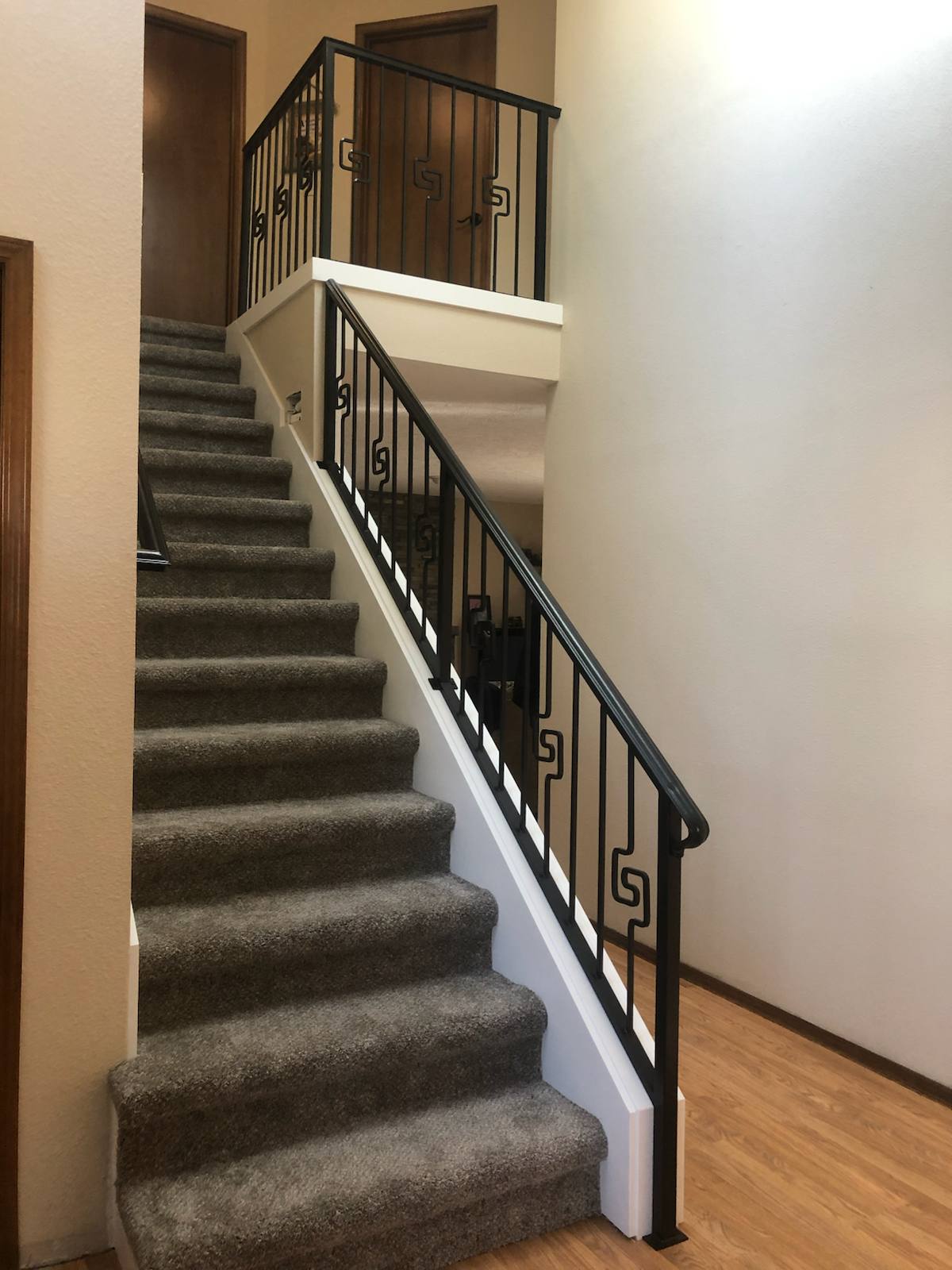 Black vertical-picket metal stair railing by Cascade Mobile Welding