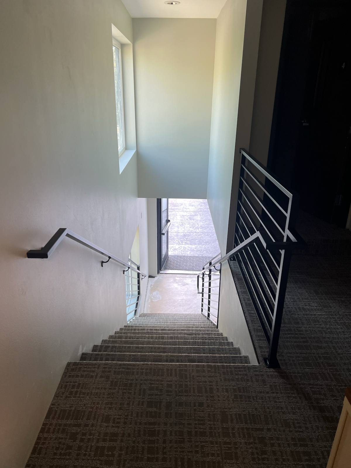 Wall-mounted black metal handrail by Cascade Mobile Welding