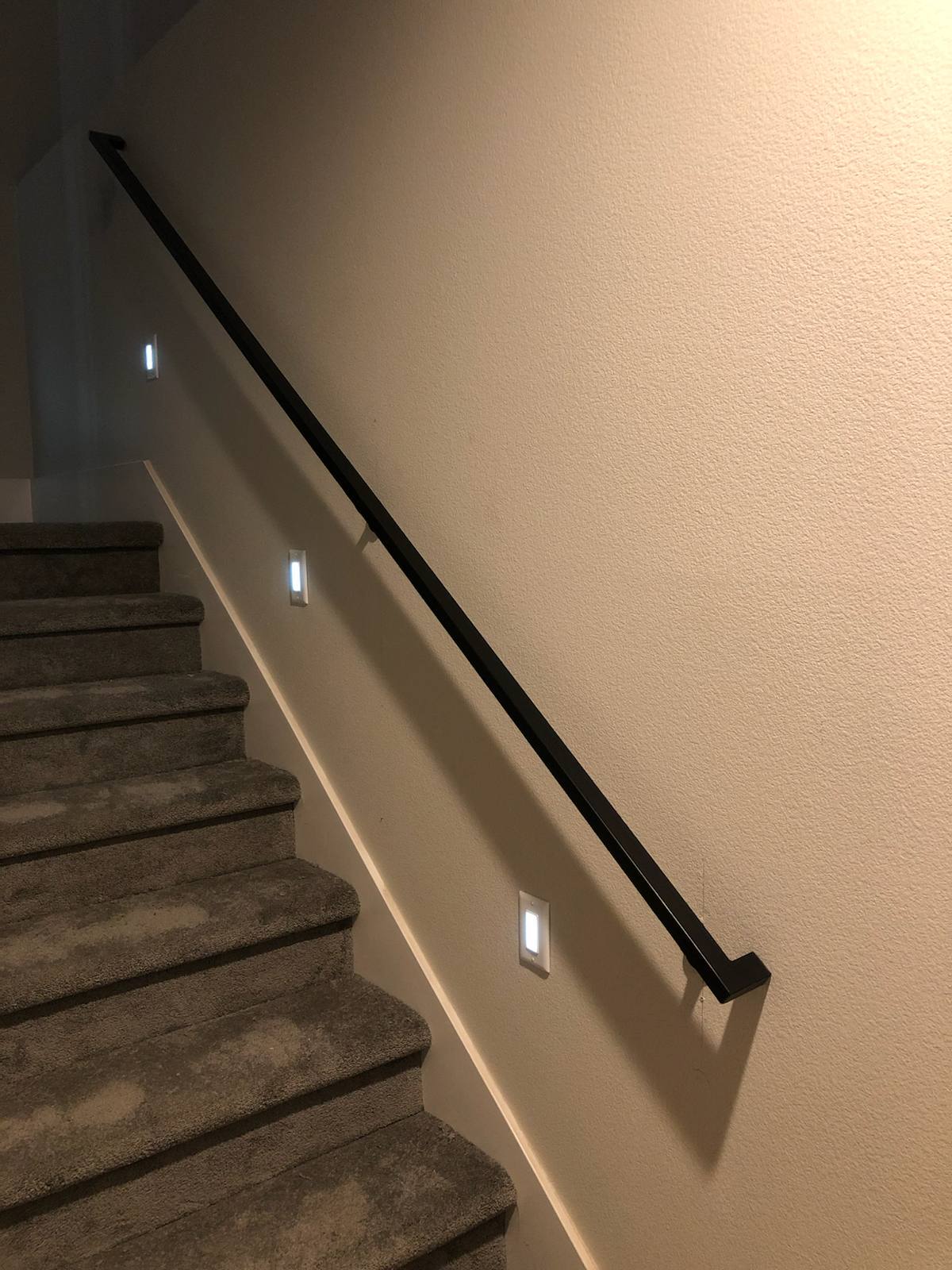 Wall-mounted black metal handrail by Cascade Mobile Welding