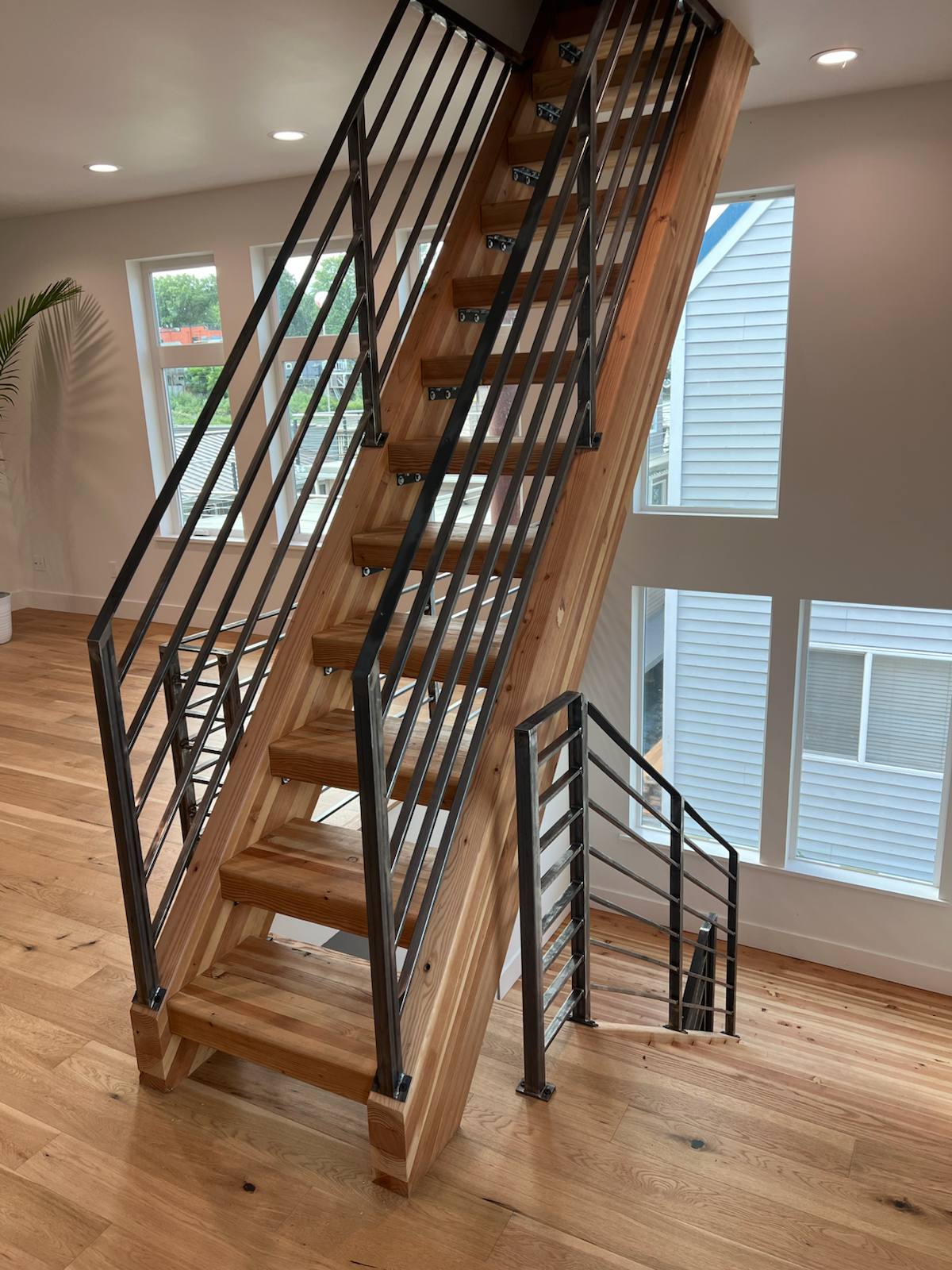 Horizontal-bar metal railing on an open-riser wood staircase — measured, welded and installed on site