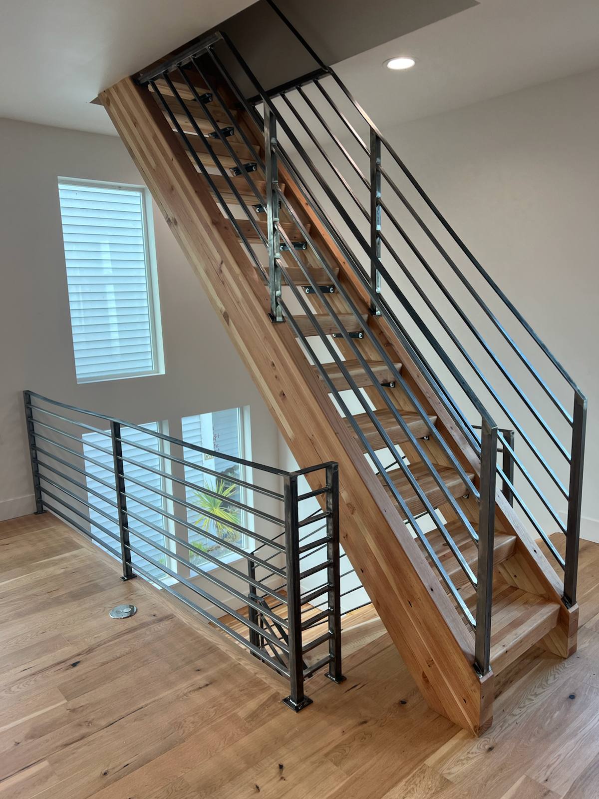 Horizontal-bar metal railing on an open-riser wood staircase in a Vancouver, WA area home
