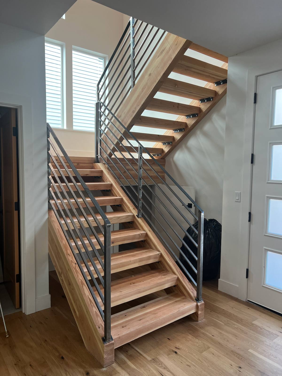 Horizontal-bar metal railing on an open-riser wood staircase — custom built and installed in Portland, OR