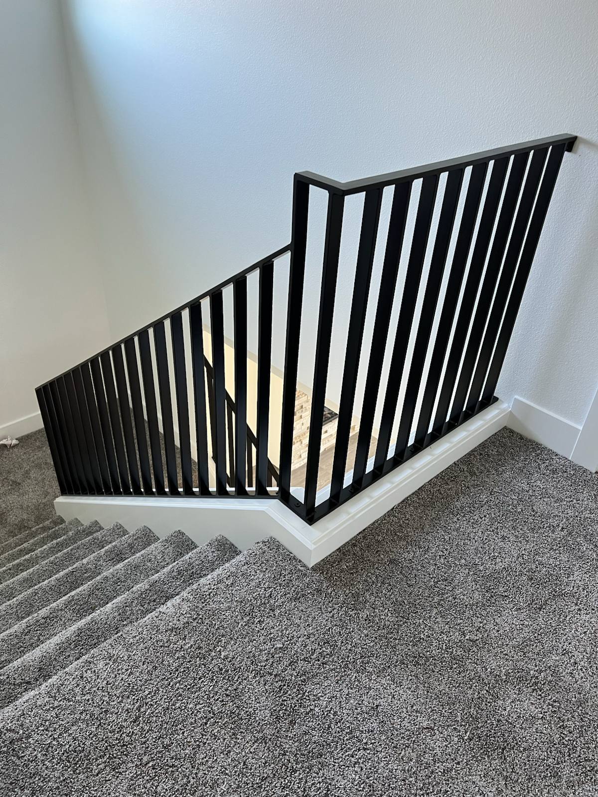 Black vertical-picket metal stair railing in a Portland-area home