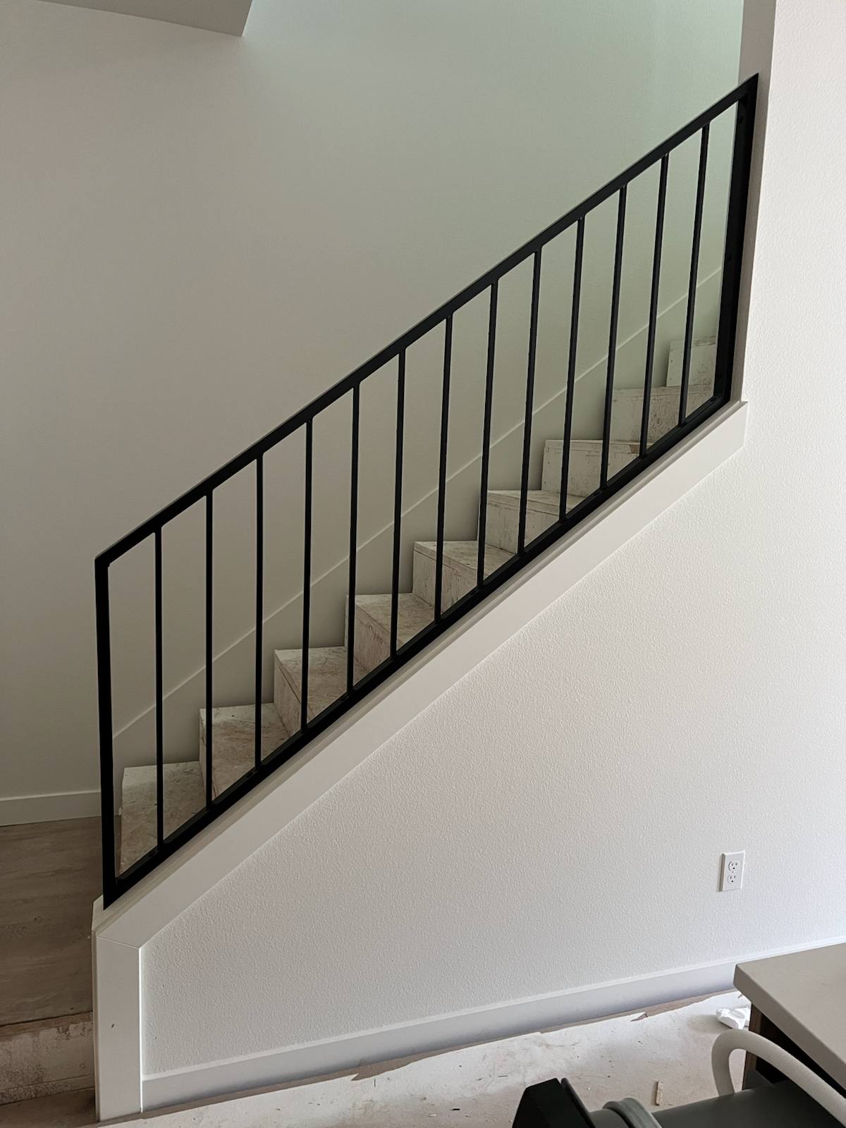 Black vertical-picket metal stair railing by Cascade Mobile Welding