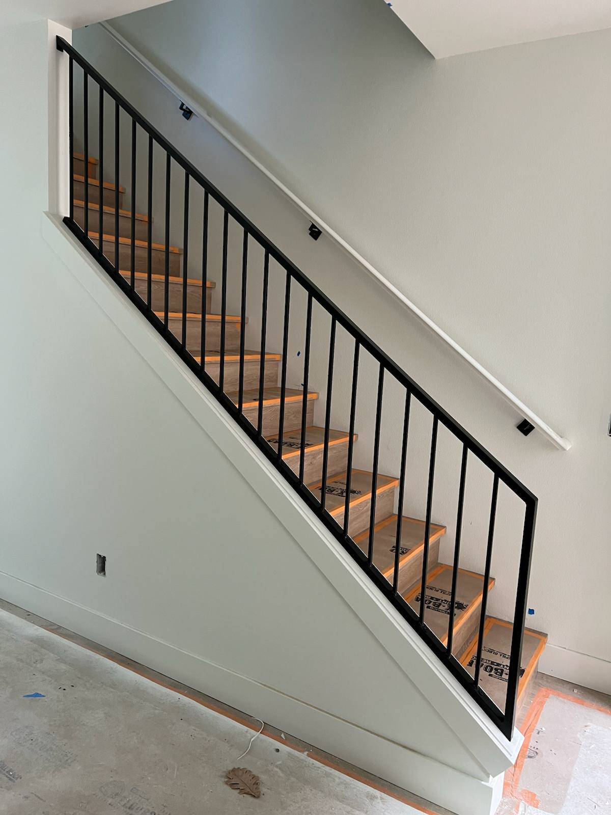 Black vertical-picket metal stair railing by Cascade Mobile Welding