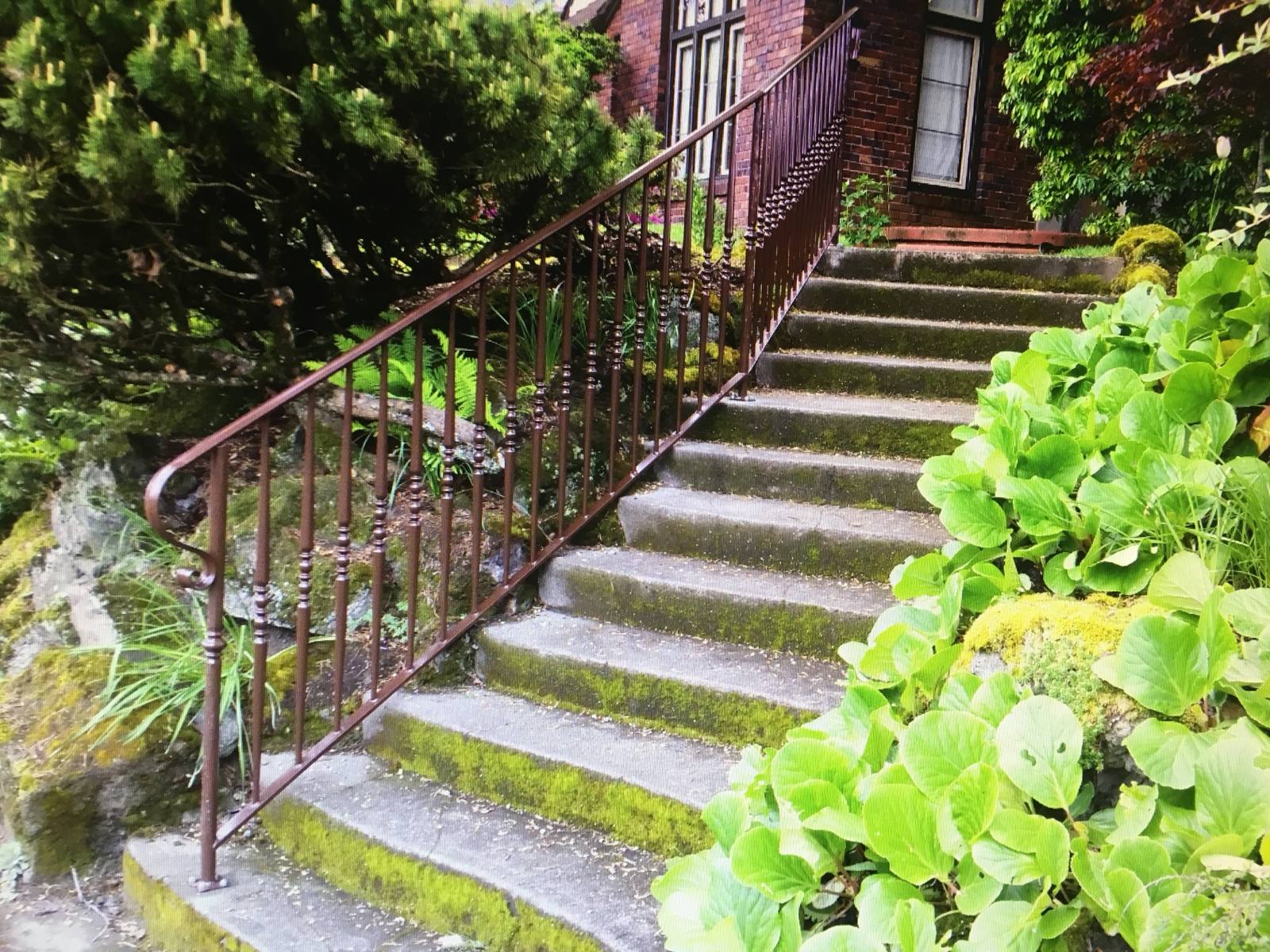 Black metal handrail on concrete front steps — welded and installed on site