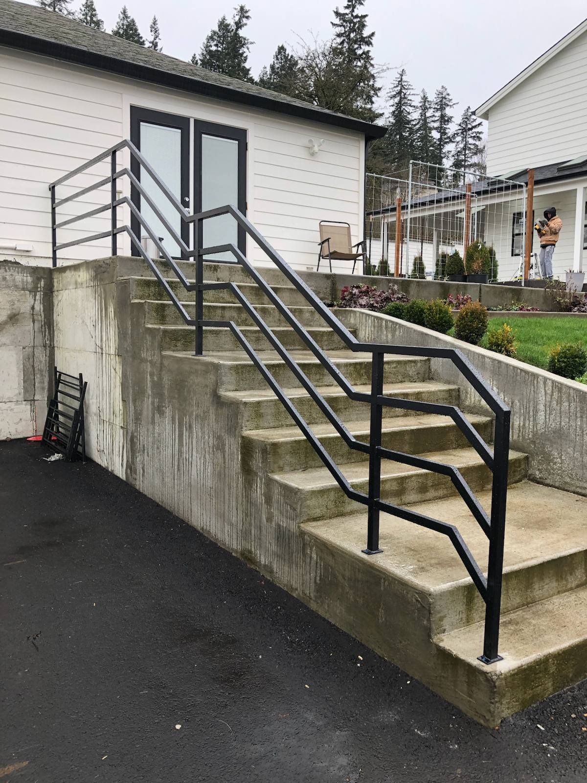 Black metal handrail on concrete front steps in a Portland-area home