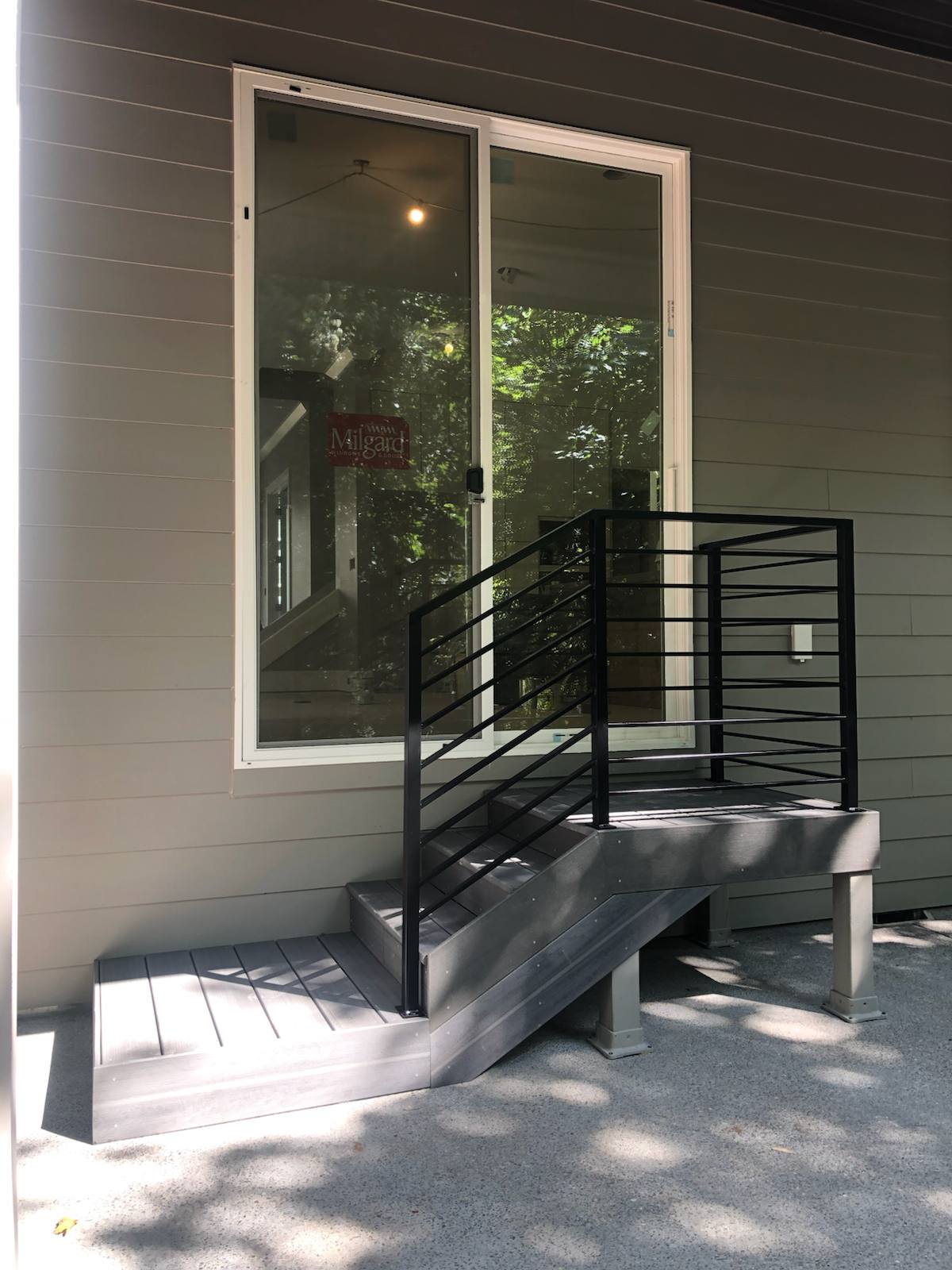 Black metal handrail on concrete front steps by Cascade Mobile Welding