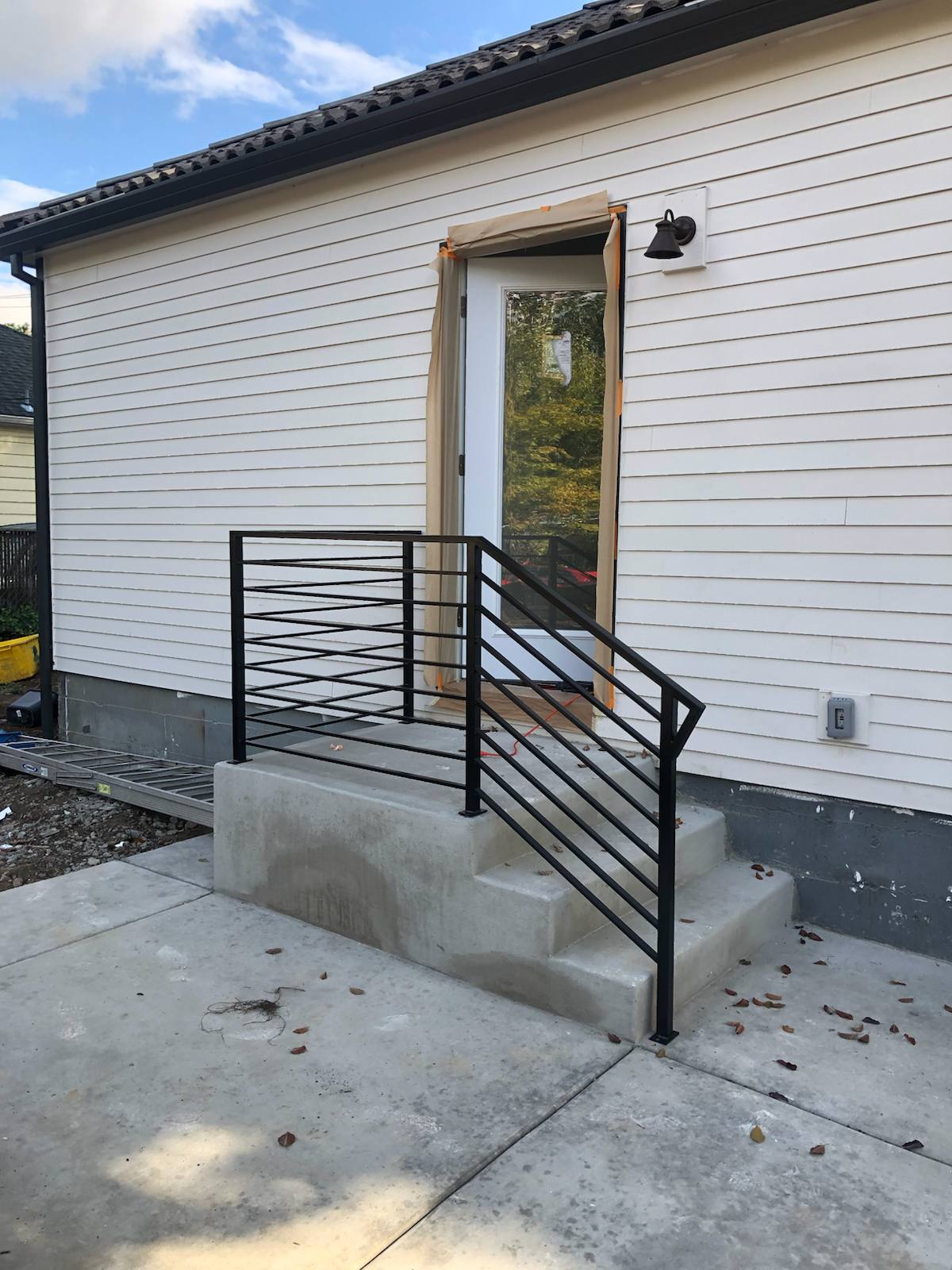 Black metal handrail on concrete front steps — welded and installed on site