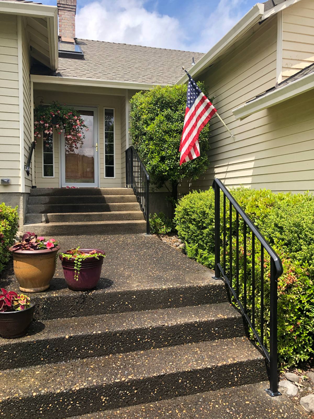 Black metal handrail on concrete front steps — welded and installed on site