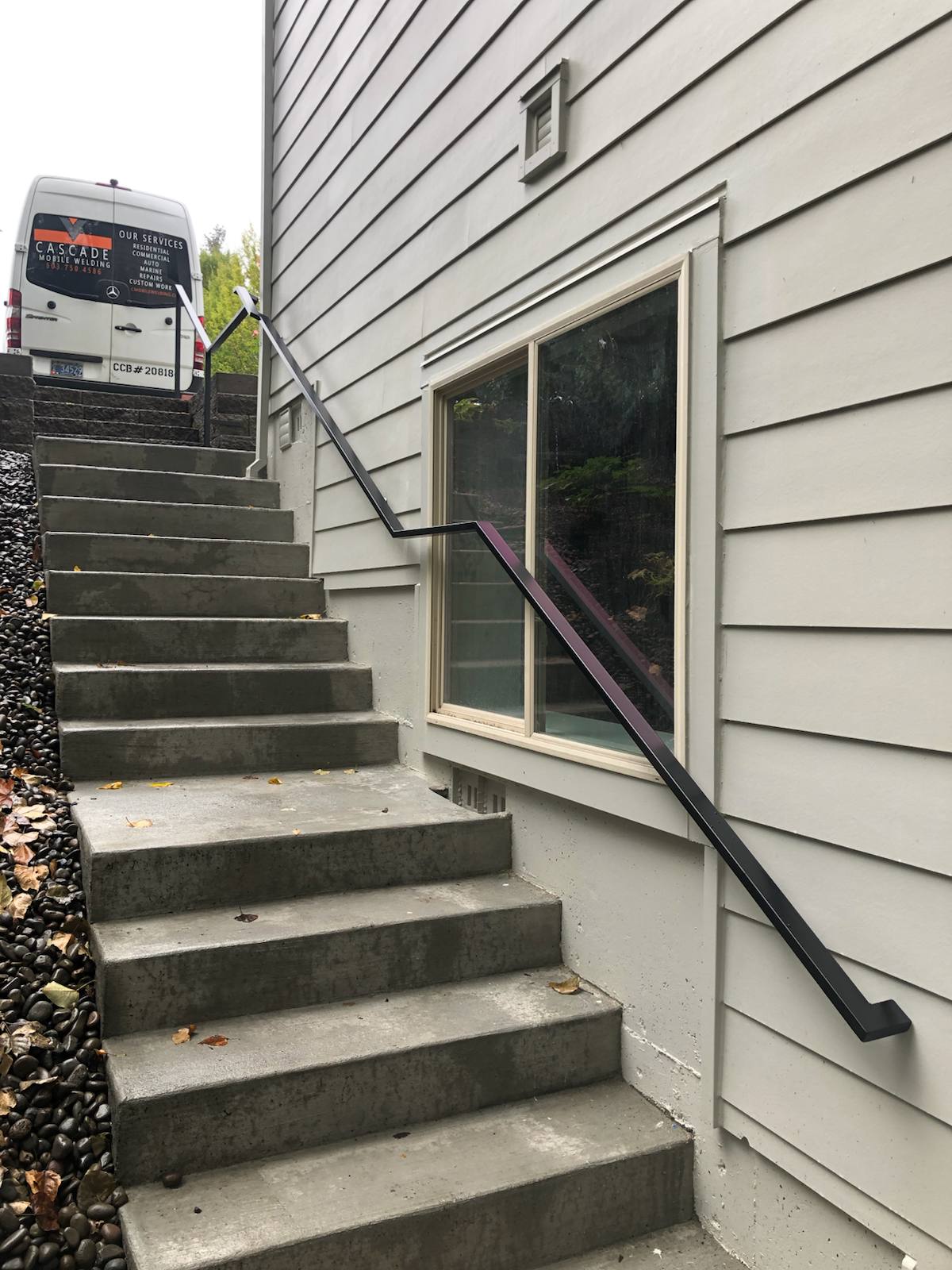 Black metal handrail on concrete front steps — custom metalwork, Portland