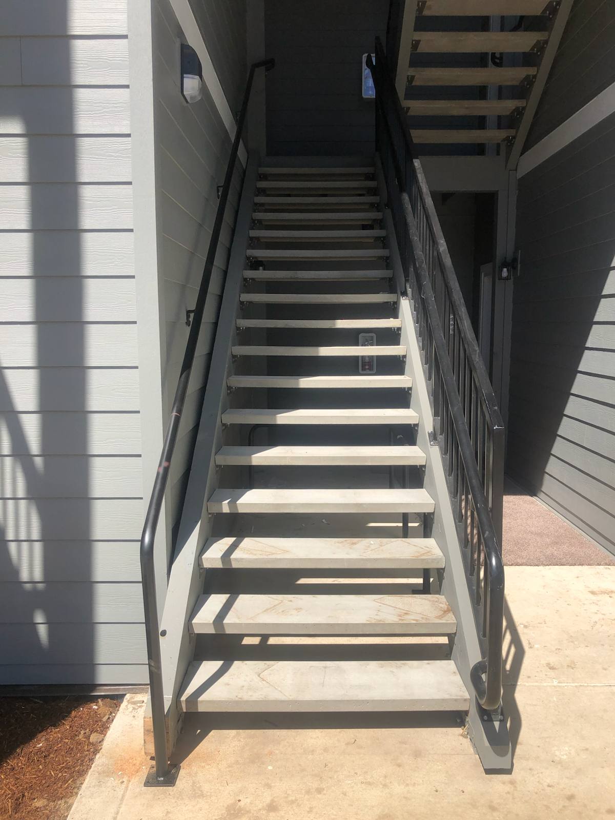 Metal railing on a multi-level exterior staircase by Cascade Mobile Welding