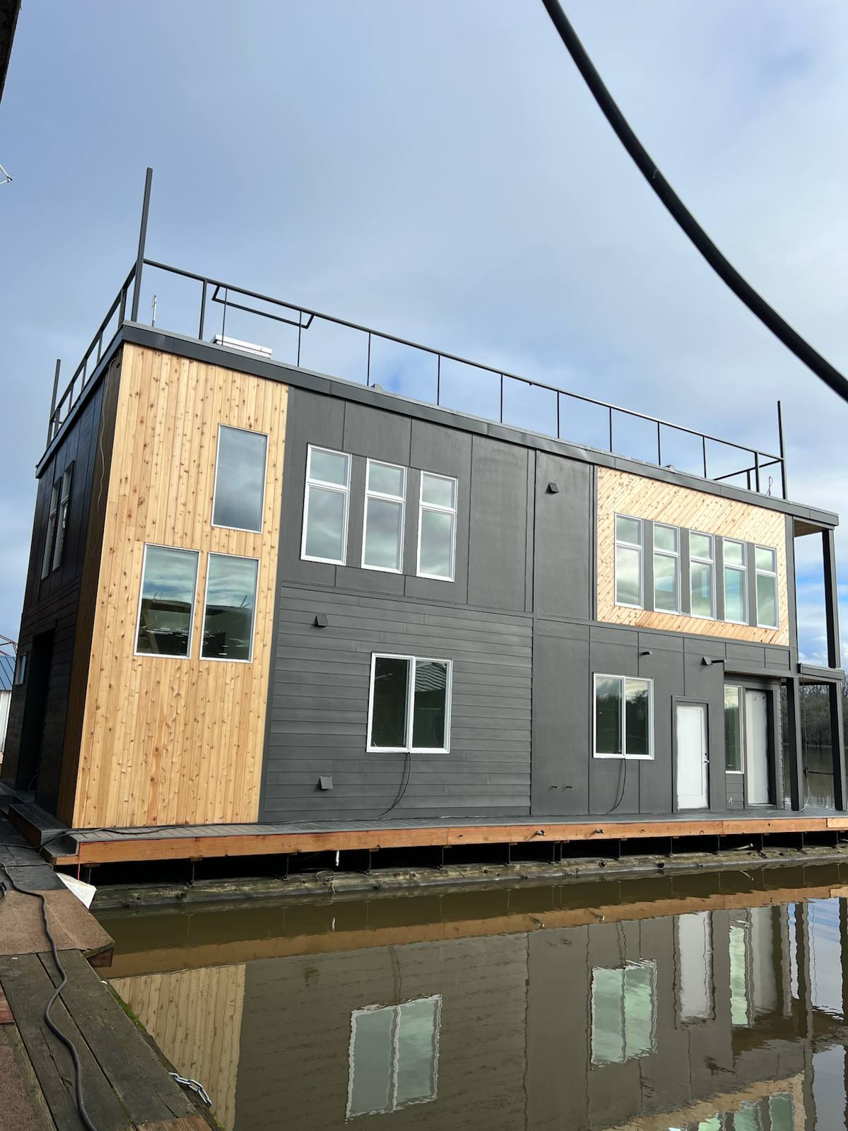 Black metal rooftop deck railing on a floating home — welded and installed on site