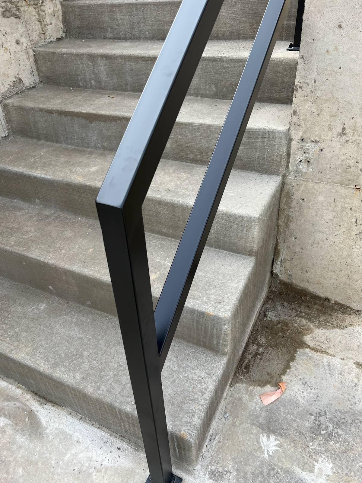 Black metal handrail on concrete front steps — welded and installed on site